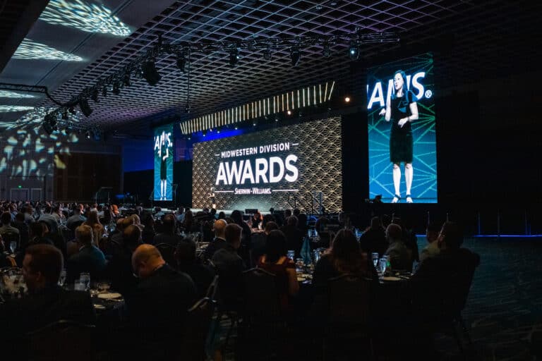 Awards stage at Sherwin Williams event with large screens